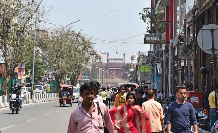 Crowded street in Old Delhi leading towards the historic Red Fort monument under a clear sky.