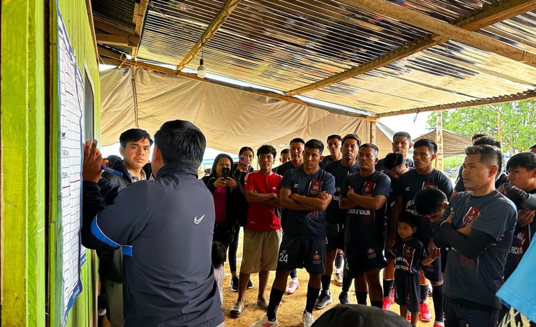 Soccer team members of Roger Bardales Mokanranko team in uniforms gather under a tin roof