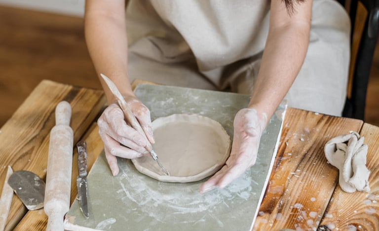 Artesana tallando para dar forma a un plato de cerámica en un taller profesional de alfarería.