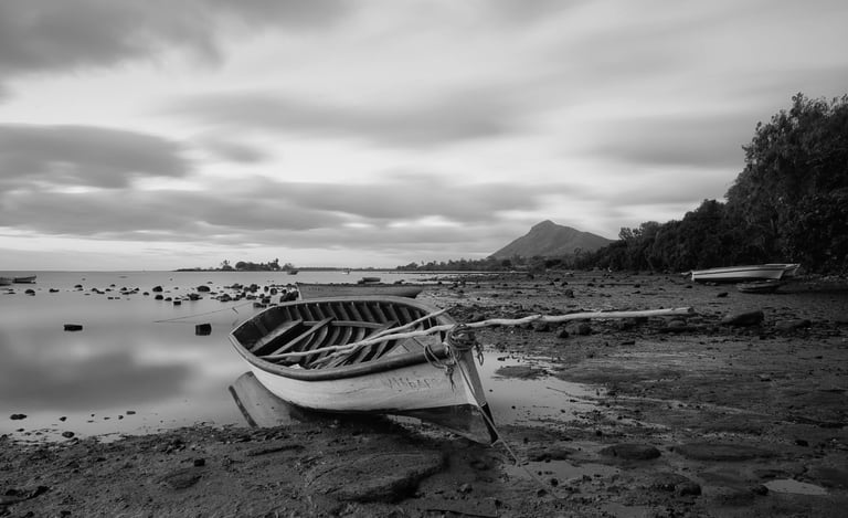 Long exposure shot of a wooden boat on a rocky shoreline at Petite Case Noyale in Mauritius