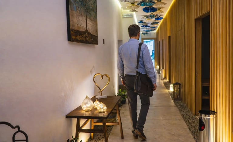 a man walking down a hallway with a table and chairs
