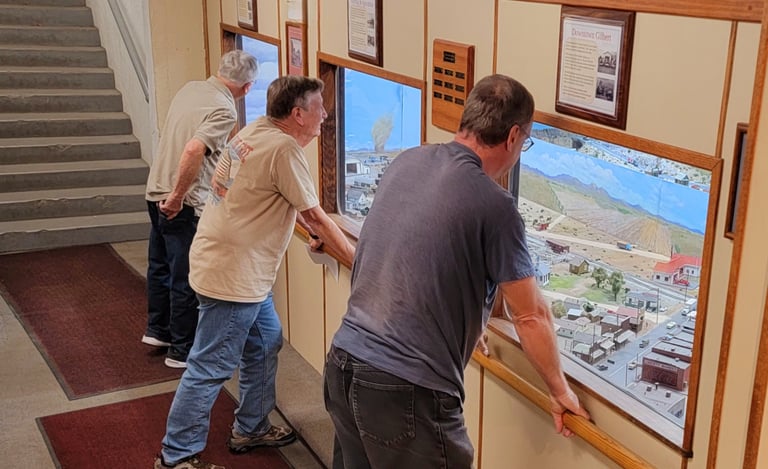 Viewing gallery windows with vistors looking at the model train layout