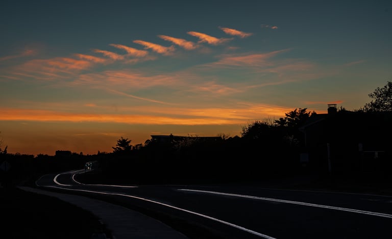 a  dark sunset scene of a road with a car on the horizon, old montauk highway