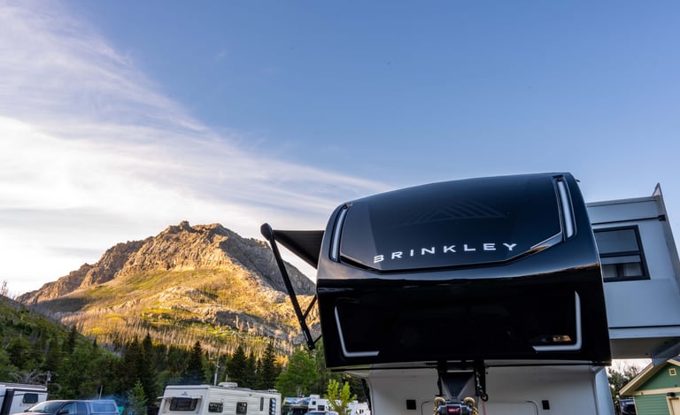 Brinkley fifth wheel camper at Waterton Lakes Campground with mountains in the background.