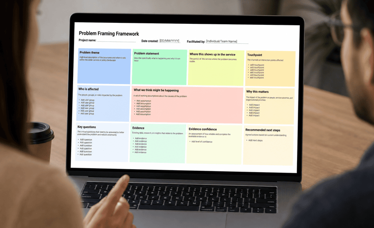 A woman and a man look at a laptop displaying a Problem Framing Framework
