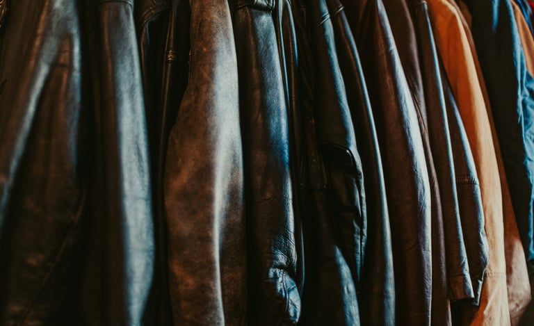 A collection of vintage leather jackets hanging on a rack in a boutique clothing store.