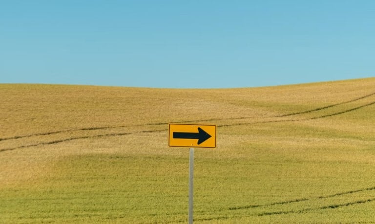 Ein weites grün-braunes Feld mit einem Pfeil nach rechts im Vordergrund