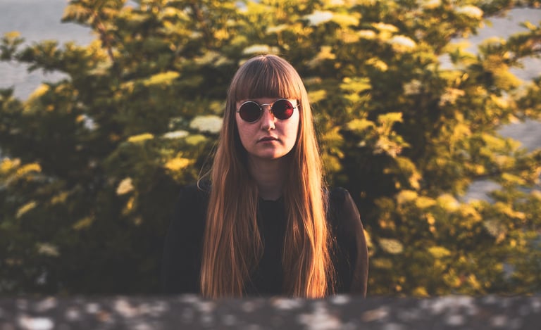 a woman with long hair and sunglasses in front of a brush