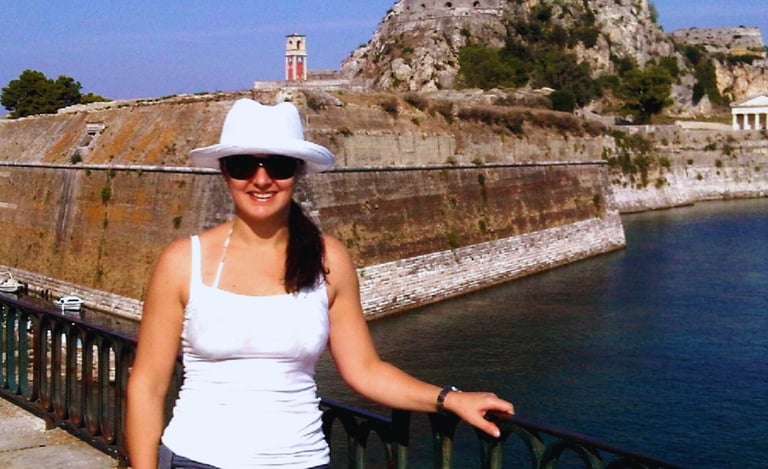 Autora diante da Fortaleza Antiga de Corfu, com a imponente estrutura histórica ao fundo.