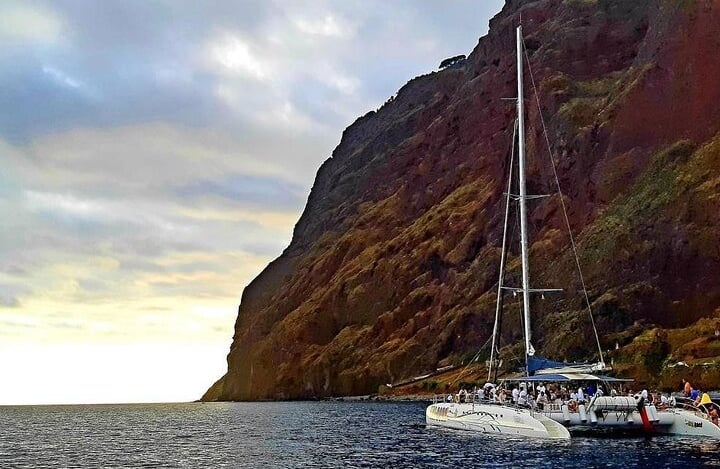 Sea Born catamaran sailing beneath the cliffs of Cabo Girão, Madeira.