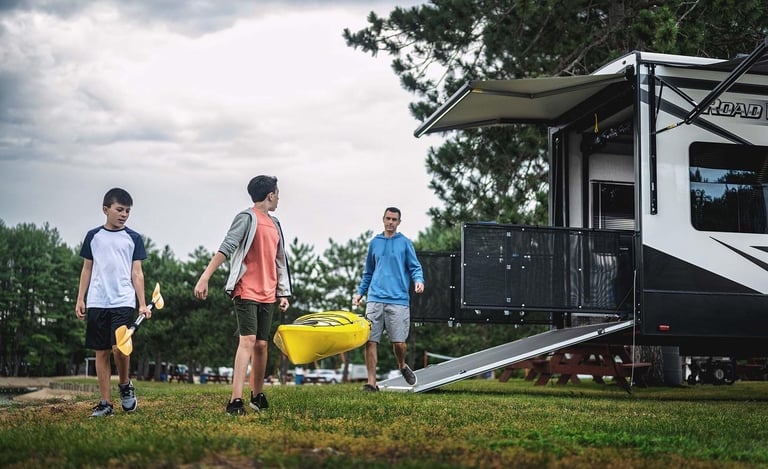a group of people walking around a trailer carrying a canoe
