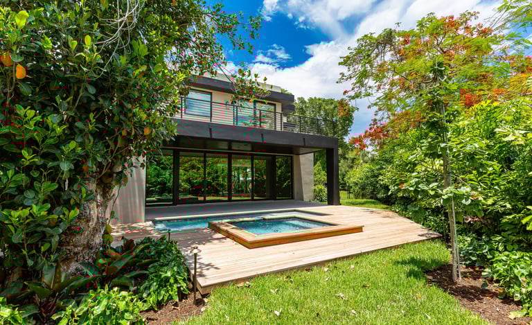 a medium sized luxury home backyard showing vibrant foliage, swimming pool with hot tub and deck