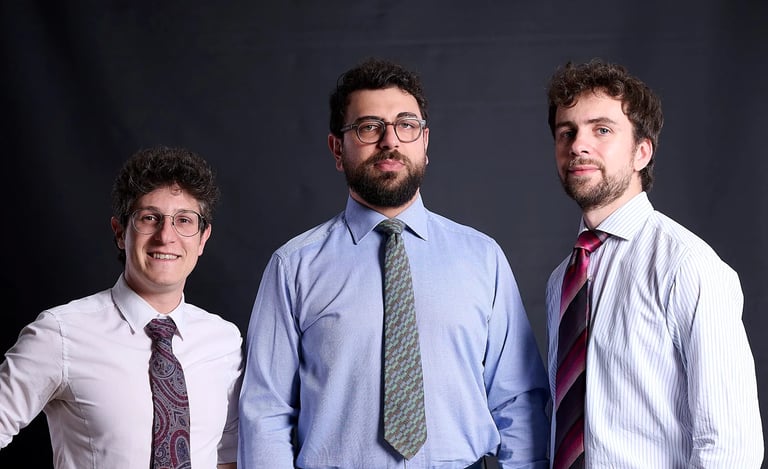 Three professional men in dress shirts and ties posing for a corporate portrait.