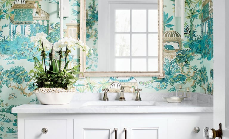 Elegant bathroom vanity with white marble top, white orchid plant, and teal chinoiserie wallpaper.