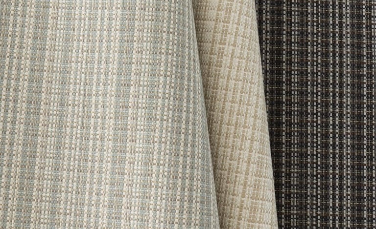 Textured woven upholstery fabric samples in neutral shades of beige, grey, and charcoal.