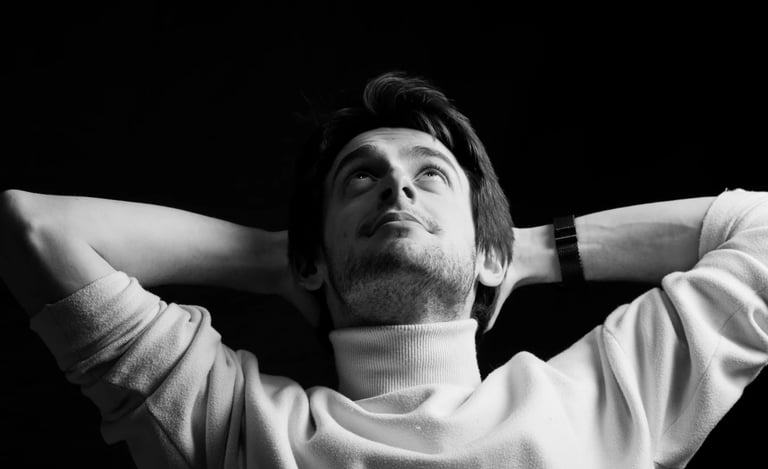 Un jeune homme décontracté les bras derrière les tête en photo noir et blanc de studio