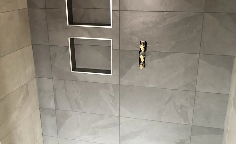 Modern tiled shower wall with recessed storage niches during bathroom renovation in Brighton.