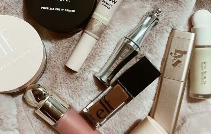 Productos de maquillaje de e.l.f., putty, Halo Glow y Rare Beauty sobre una alfombra.