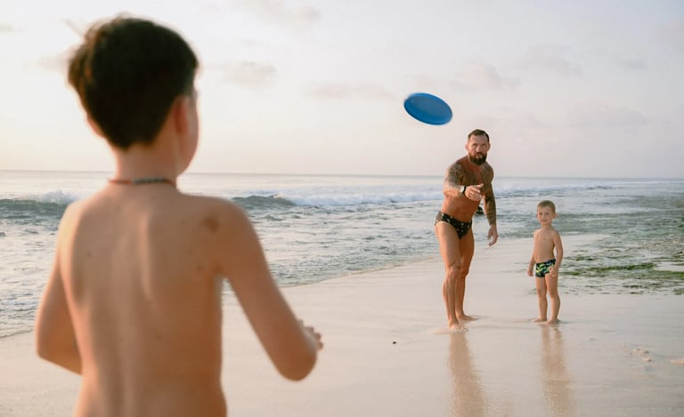 Young boy playing frisbee on the beach during a relaxed family photography session at Dreamland Beach Bali.