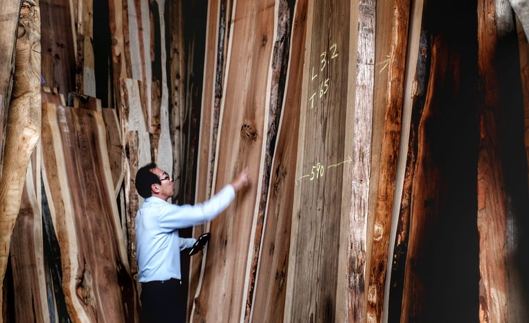 A woodworking professional inspects large live edge wood slabs in a lumber warehouse.