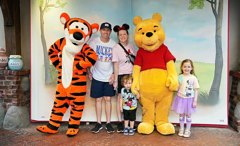 Aimee Cochrane and family pictured with Winnie the Pooh and Tigger at Disney's Magic Kingdom® inside Walt Disney World®.