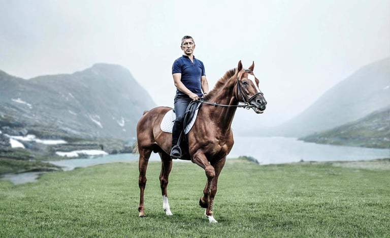 A rider on a horse in a mountain setting, embodying elegance and adventure for an equestrian brand.