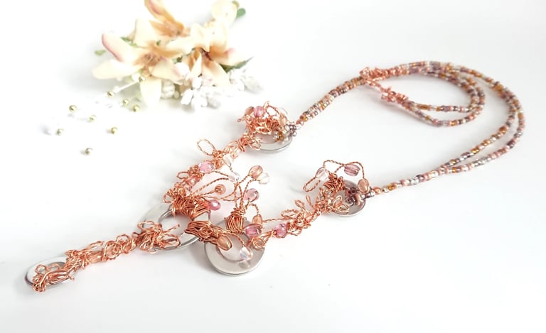 A necklace of steel washers amd copper, wrapped and twisted like flowers entwined with glass beads