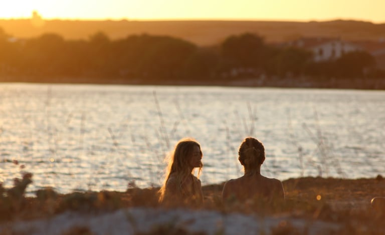 two people doing yoga on a beach with a sunset in the background
