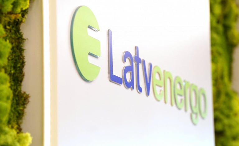 Latvenergo corporate logo mounted on a white wall with green moss decorative panels.