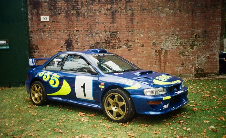 a Subaru Impreza rally car parked in front of a brick building