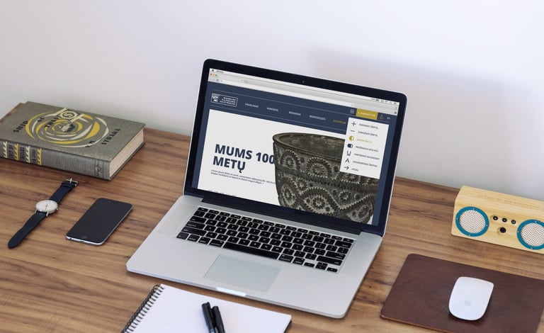 A laptop with the front page of the museum's website is open.