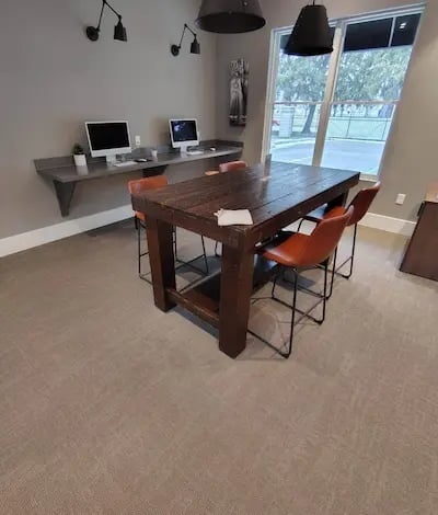 Picture of an office with two computer monitor and a table with four red chairs