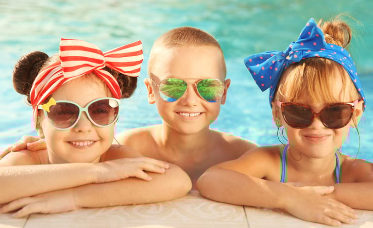Three kids wearing protective sunglasses in a pool