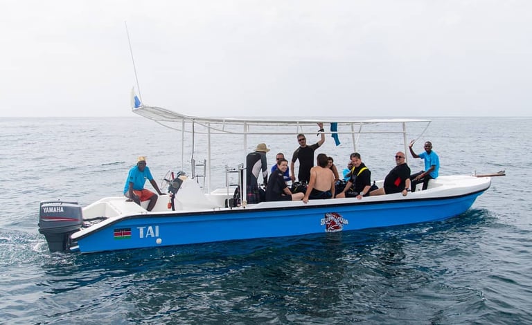 Scuba divers in wetsuits preparing for a dive on a blue boat in the Indian Ocean.