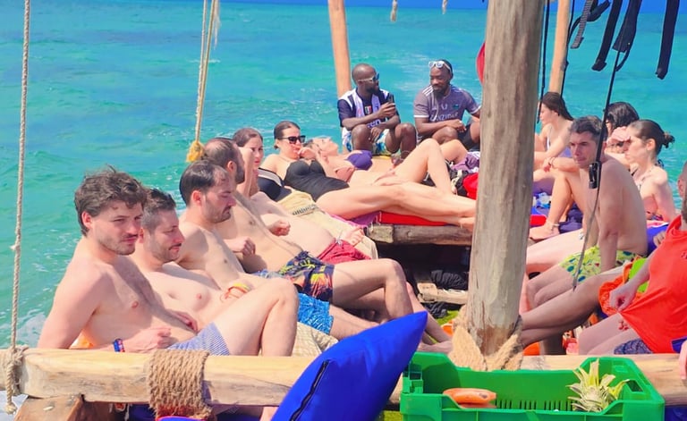 Tourists relaxing on the deck of Safari Blue Zanzibar boat tour, enjoying sun, turquoise waters, and scenic views