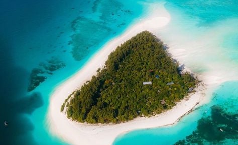 Full aerial view of Mnemba Island Zanzibar surrounded by turquoise waters and white sandy beaches.