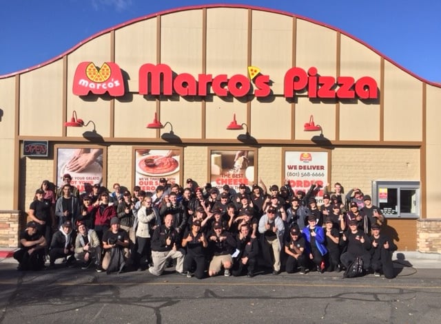Team of Marco's Pizza employees posing for a photo in front of a Marco's Pizza store.