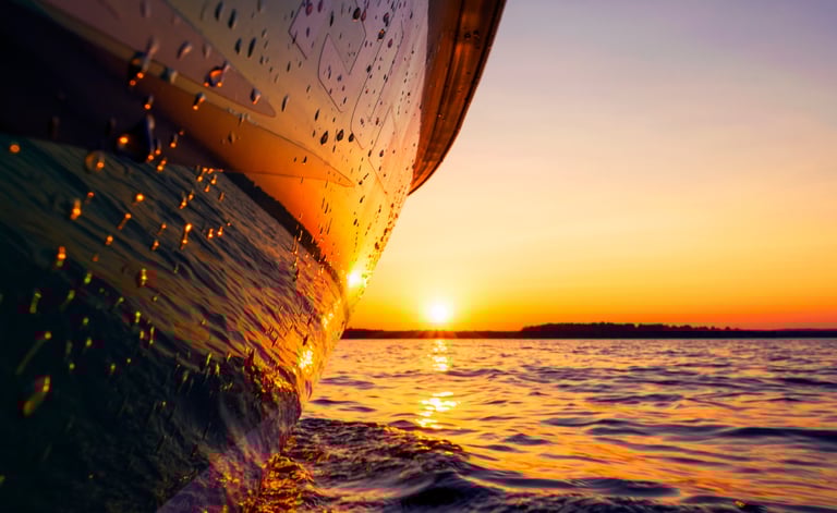 Beautiful picture of a boat hull at the waterline reflecting the gorgeous sunset.