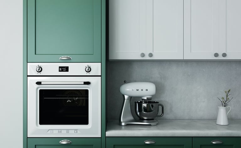 Cocina de diseño con armarios en tonos verde y blanco, electrodomésticos integrados y encimera gris.