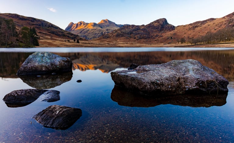 Scenic view of Blea Tarn in the Lake District with Langdale Pikes reflected in still water.