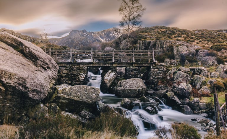 Rustic stone bridge over a mountain waterfall in Snowdonia National Park, Wales.