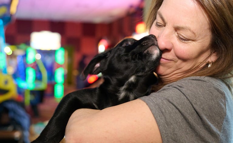 a woman is holding a black dog in her arms