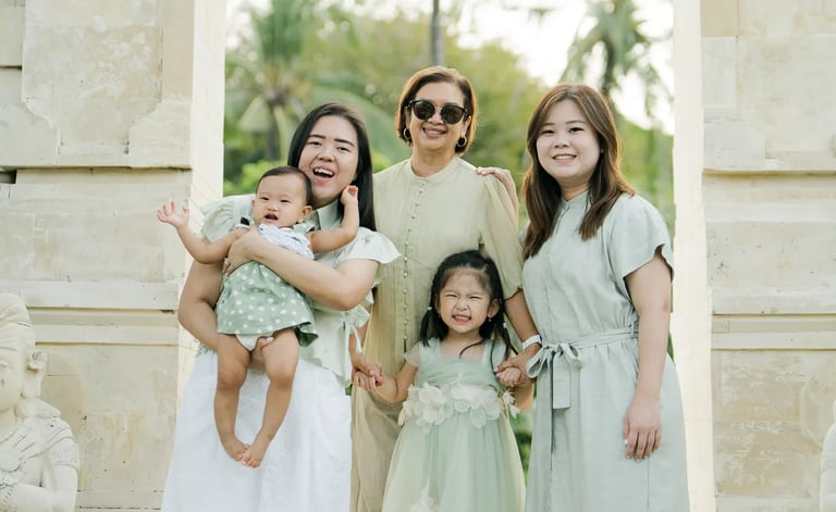 Mother and daughters posing together at a traditional Balinese entrance during a family photography session in Bali.