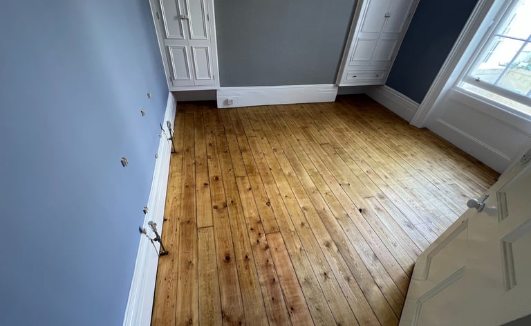 Brighton office featuring restored pine wood flooring, blue walls, and built-in white wardrobes.