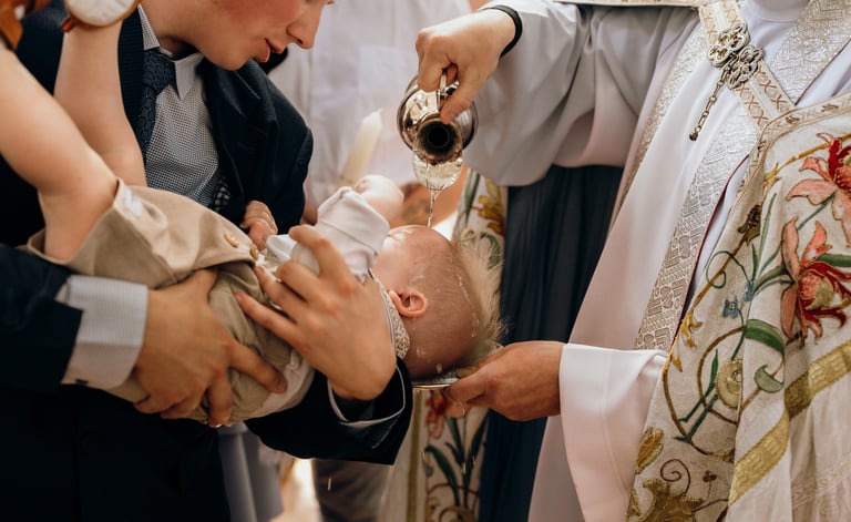 Krikštynų fotografija - kunigas krikštyja vaiką, pila jam ant galvos vandenį