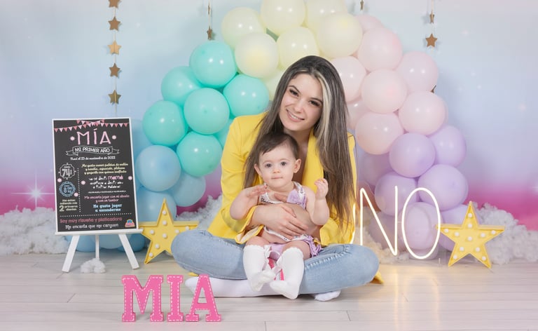 a woman holding a baby in front of a rainbow colored backdrop