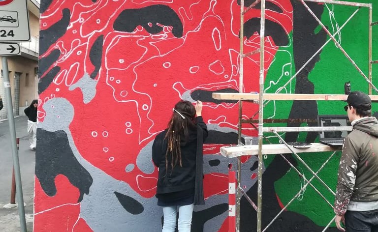 Red and green mural in progress, Poliops and collaborators painting on urban scaffolding.