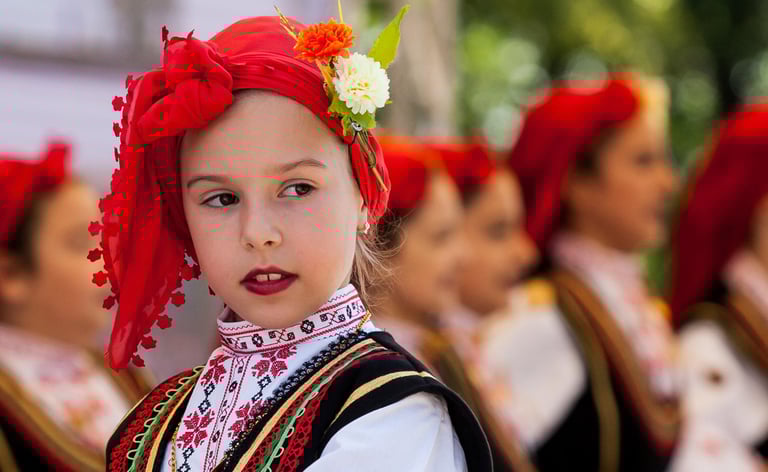 Photo of a young girl in traditional Bulgarian costume staring off the image to the right.