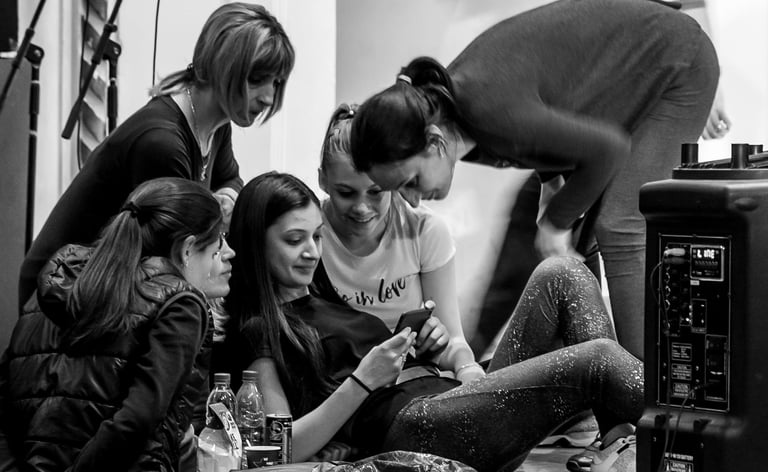 A group of performers reviewing a video on a mobile phone during a break