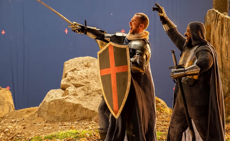 Two extras in medieval knight costumes looking to the left and cheering on a blue screen background 